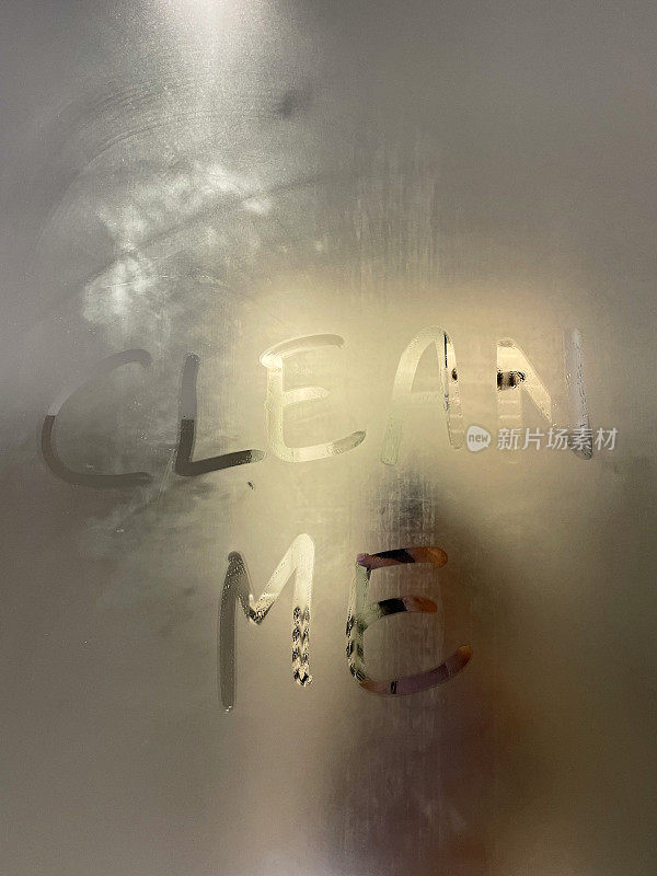 用大写字母写的“Clean Me”全画幅图像，凝结在一面镜子的蒸汽玻璃上，聚焦于前景